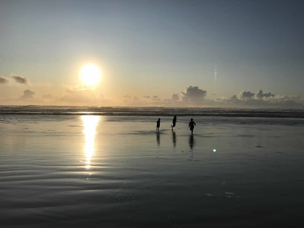 Three of our children run along Nye Beach near sunset.