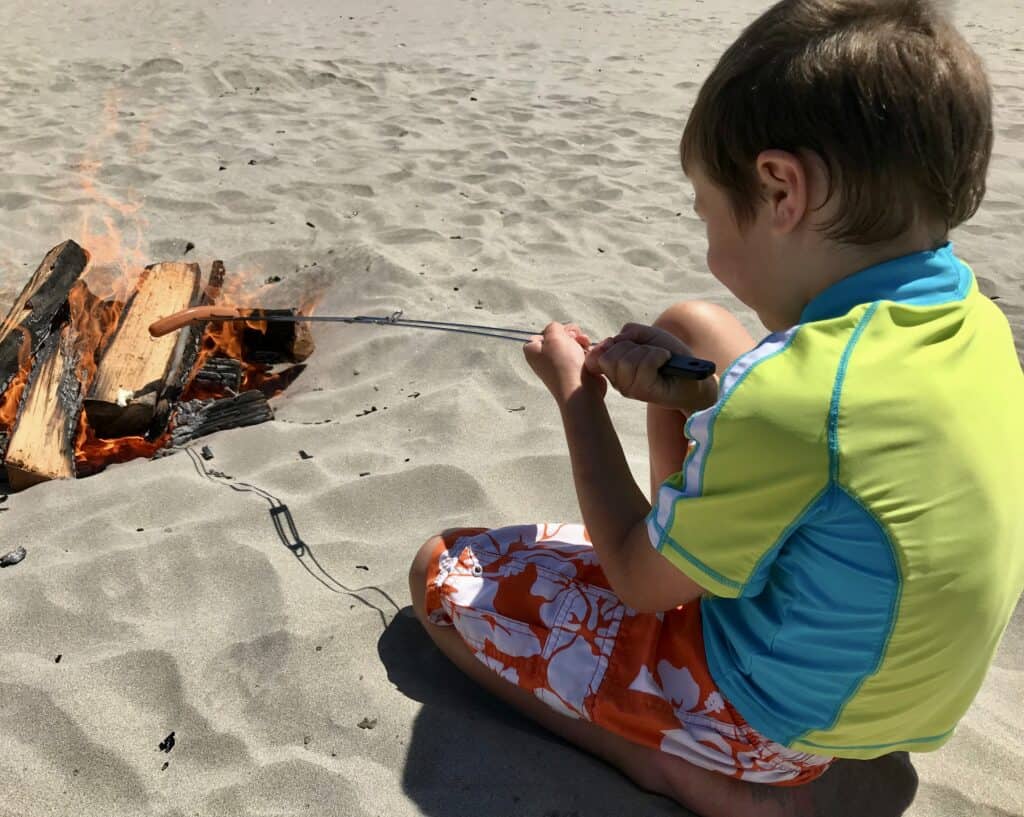 Our young son enjoys roasting a hot dog over a fire at Seaside Beach.