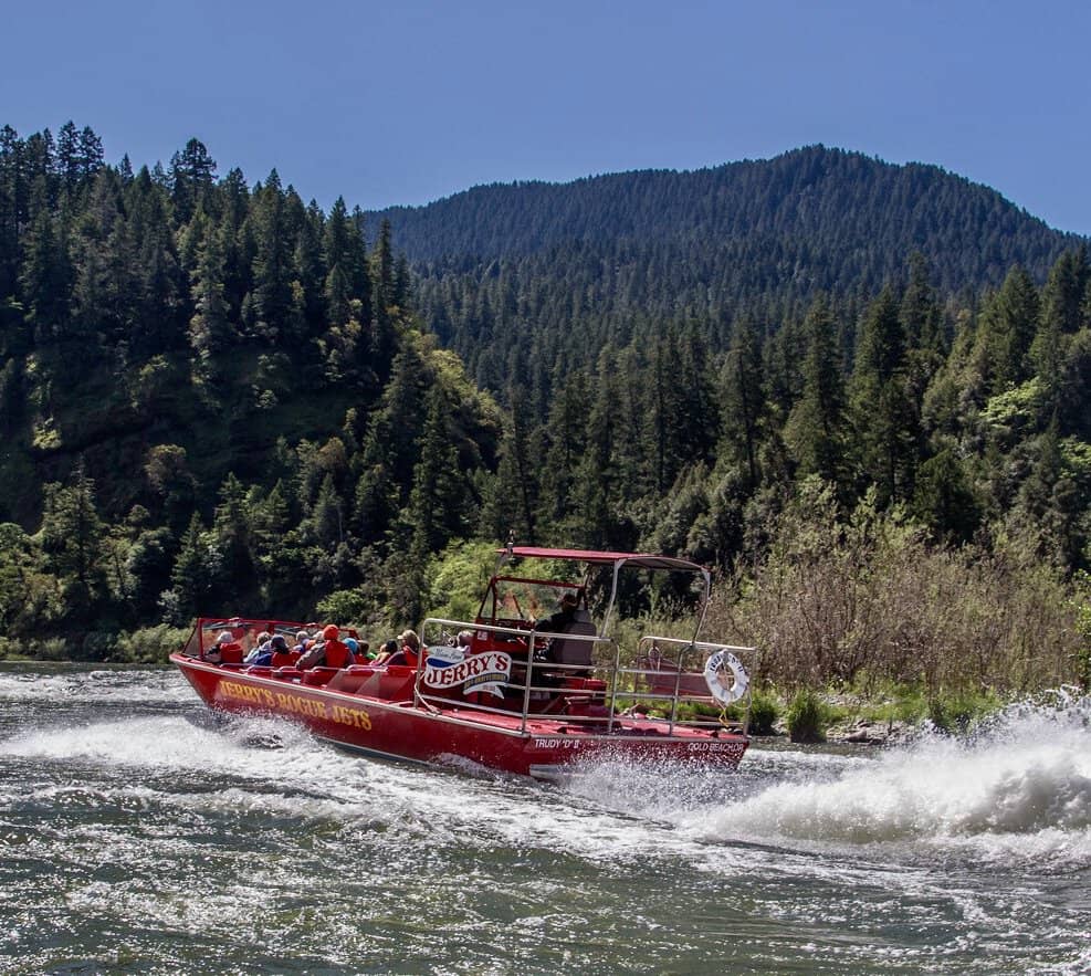 A red jet boat speeds up the Rogue River.