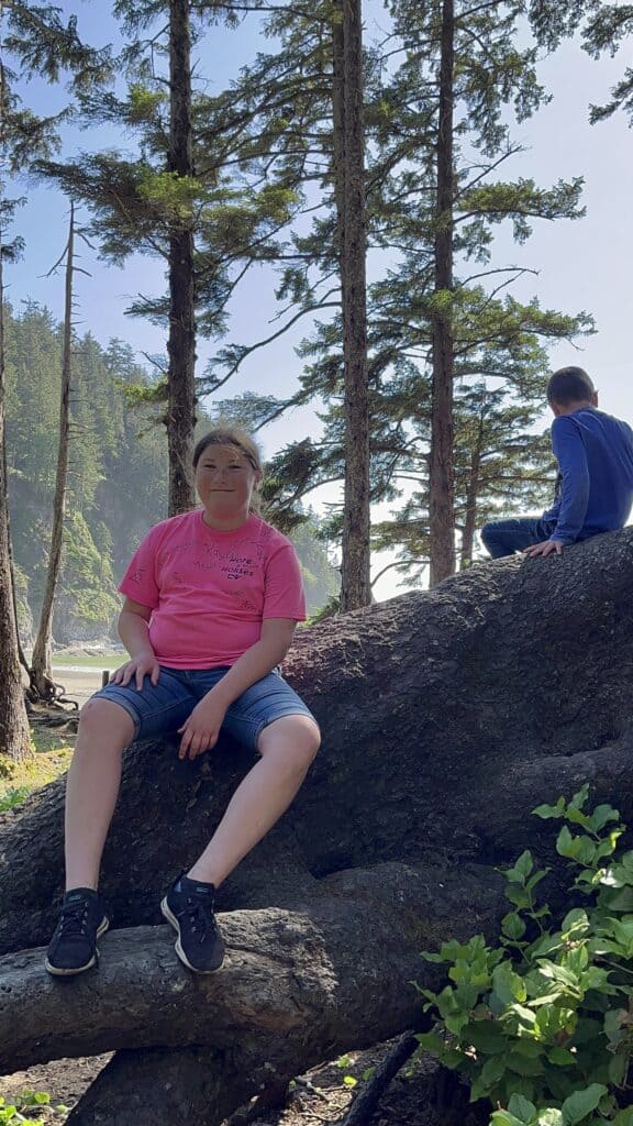 Our daughter smiles as she sits on an enormous root in the old growth forest that leads to Short Sand Beach in Oswald West State Park.