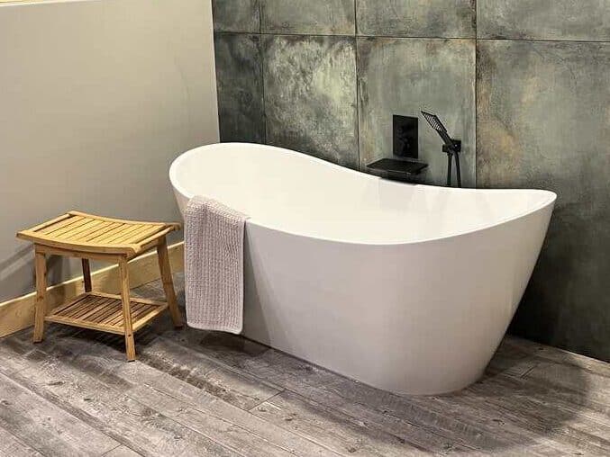 A soaking tub with bench and towel next to it.