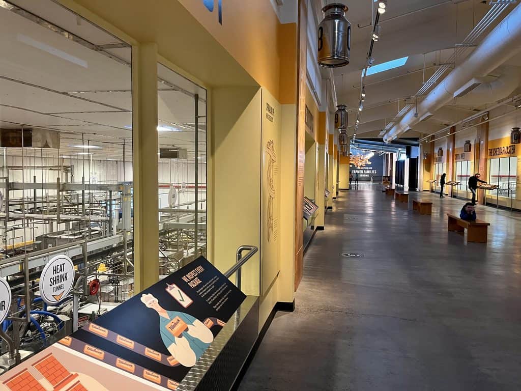 Colorful interpretive signs stand near windows that overlook various parts of the Tillamook Cheese Factory.