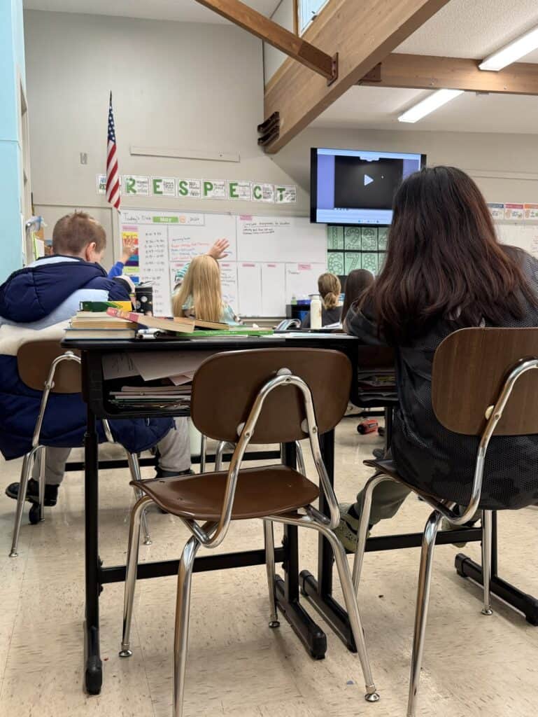 Students in a classroom as seen from the back of class.
