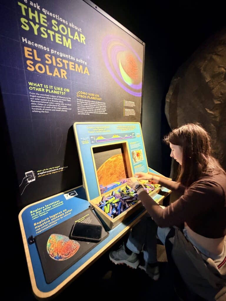 Teen girl studies an English and Spanish display of The Solar System topography.